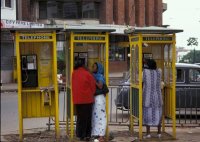 ナイロビの一角の公衆電話。故障中のものがけっこうある。これを撮影した2001年でも、すでに携帯電話はあるていど普及していたと思う。現在は携帯電話なんて珍しくもない。街角の電話もまだ健在だが、隣国ウガンダの首都Kampalaやタンザニアの都市Dar-es-Salaamでも、近年では市販の電話機を机に置き、キオスク内や炎天下キャップを被って商売するスタイルが多く見受けられ、利用者を得ている。こうしたクラシックなphone boxのある光景もいずれなくなるか？
撮影：白石壮一郎, 2001年
